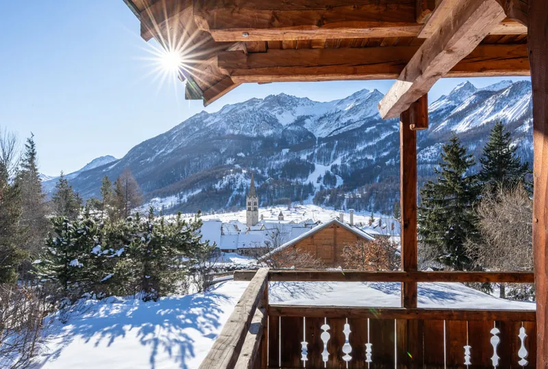 A wooden chalet balcony surrounded by snow