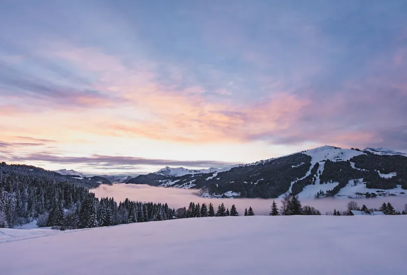 a pastel sky reflects off a ski resort scene and fresh snow at dusk